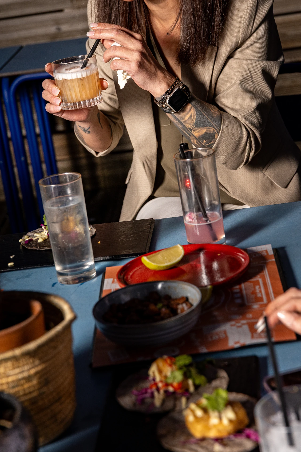 Cliente tatouée tenant un cocktail signature à table