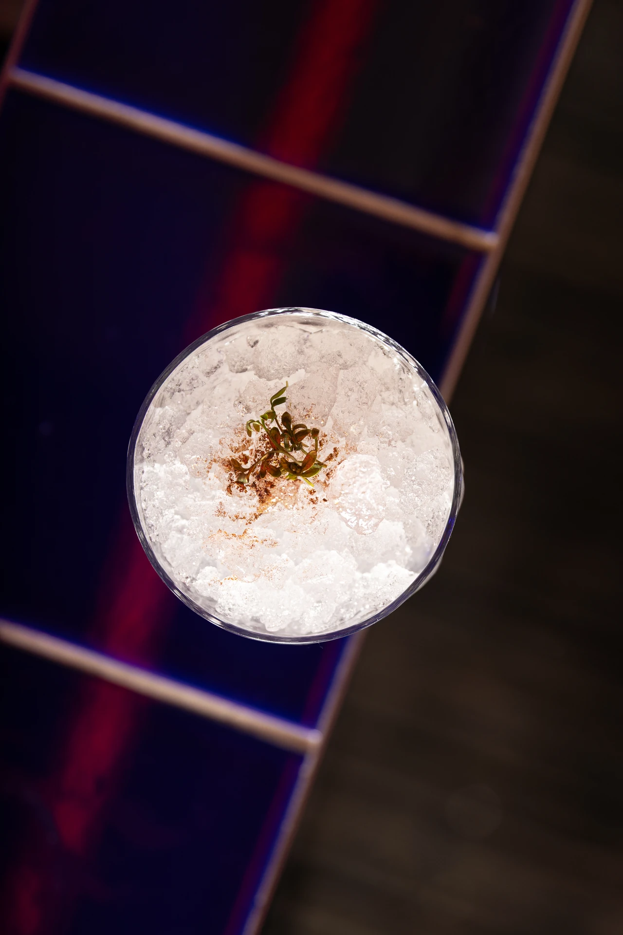 Cocktail vu de haut, glace pilée et micro-pousses sur carrelage bleu et rouge