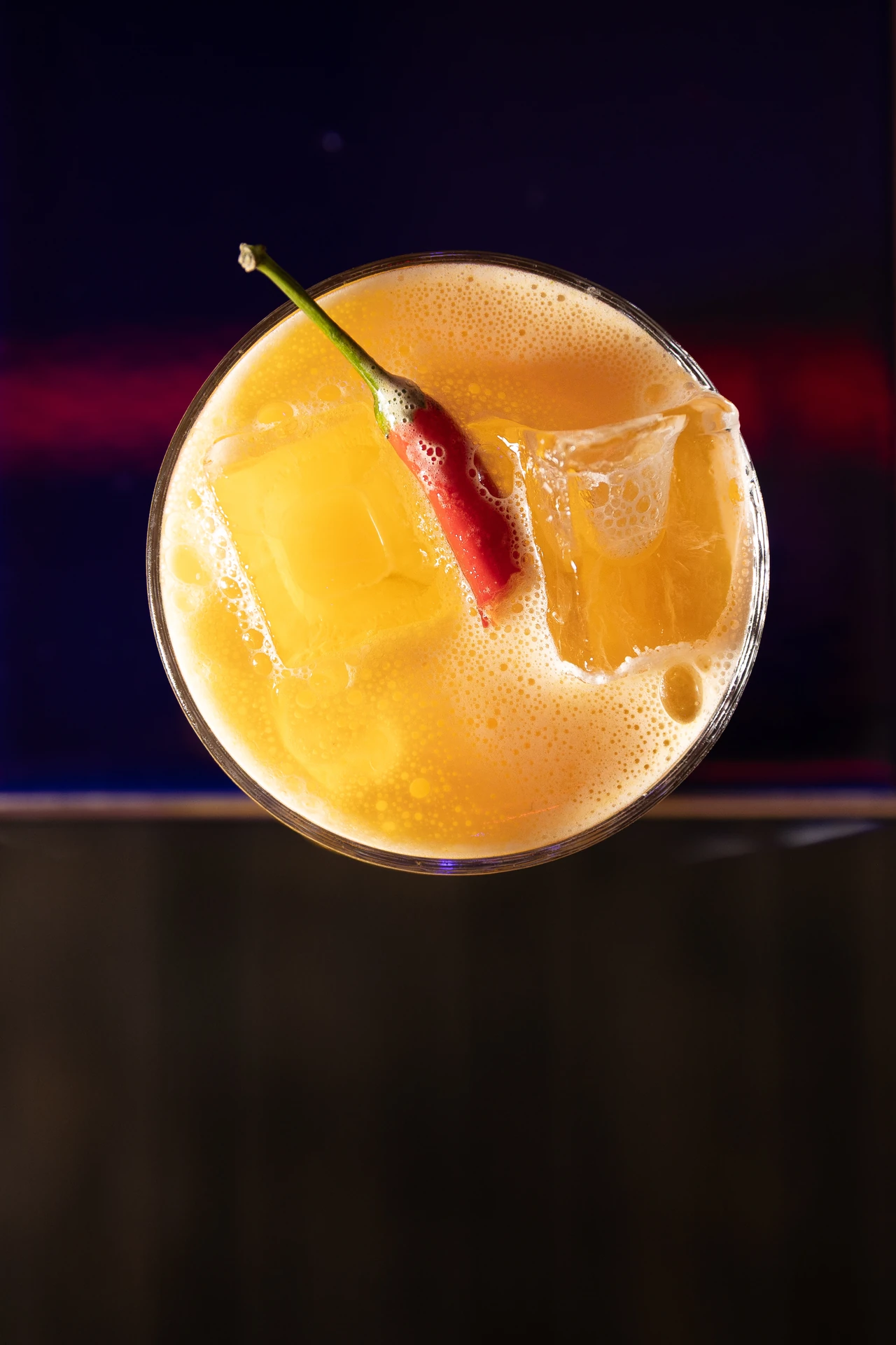 Vue de dessus d'un cocktail mangue piment sur fond rouge néon