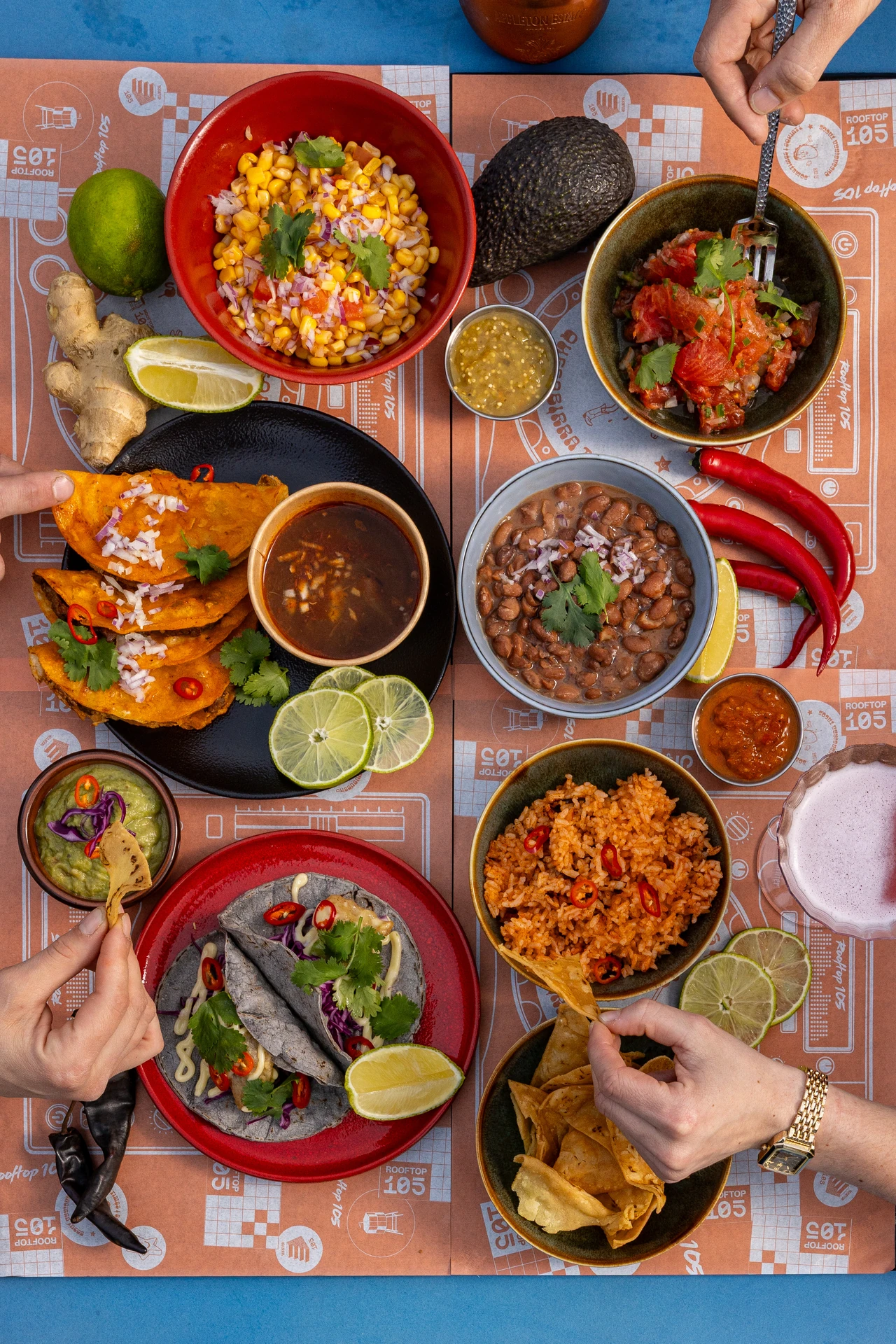 Festin mexicain à partager, mains plongeant dans les bowls au Rooftop 105