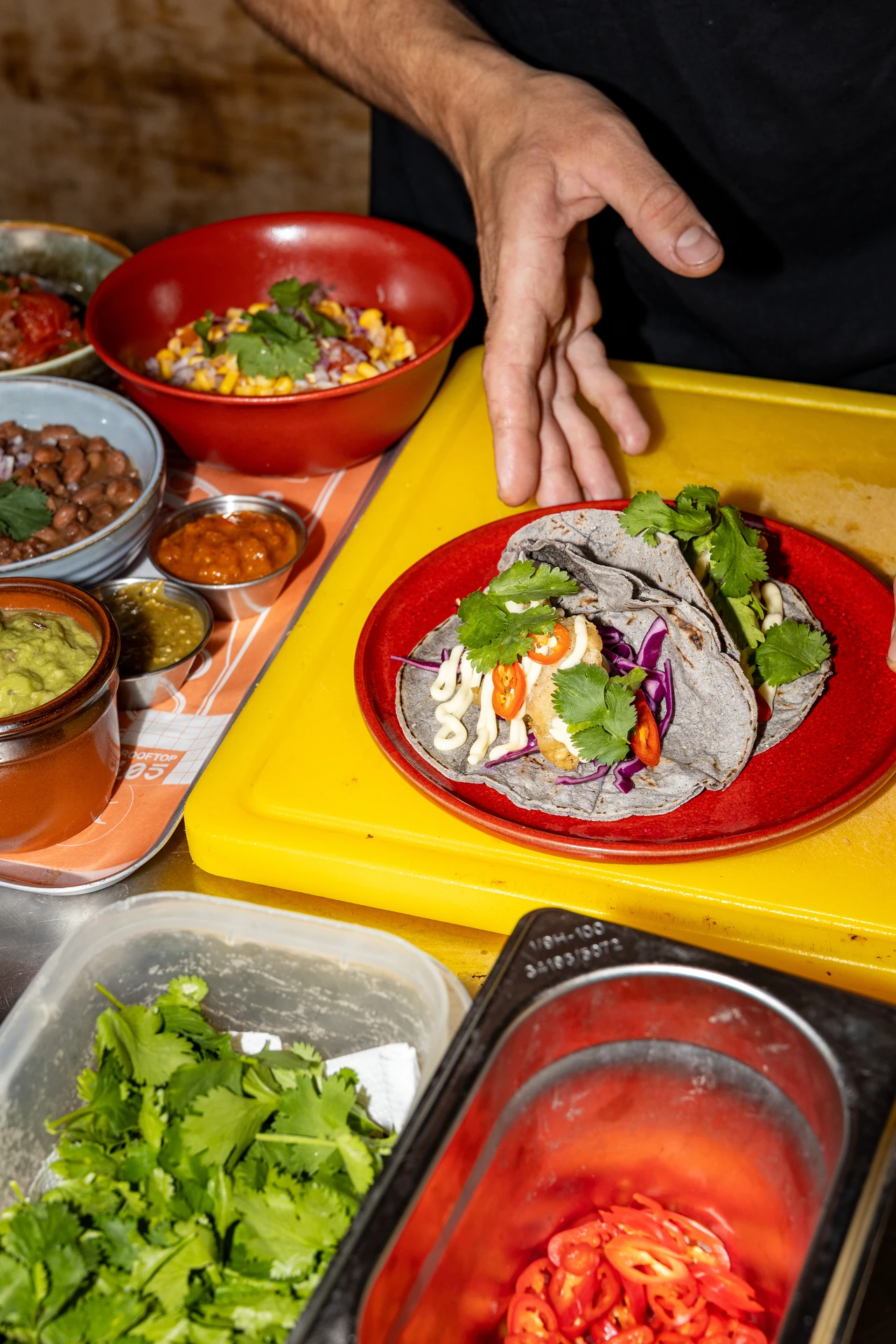 Préparation des tacos bleus en cuisine, plateau jaune et bowls de garnitures